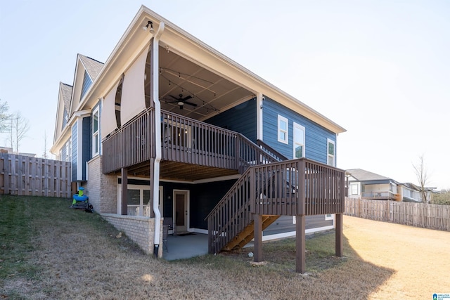 back of property with a deck, ceiling fan, and a lawn