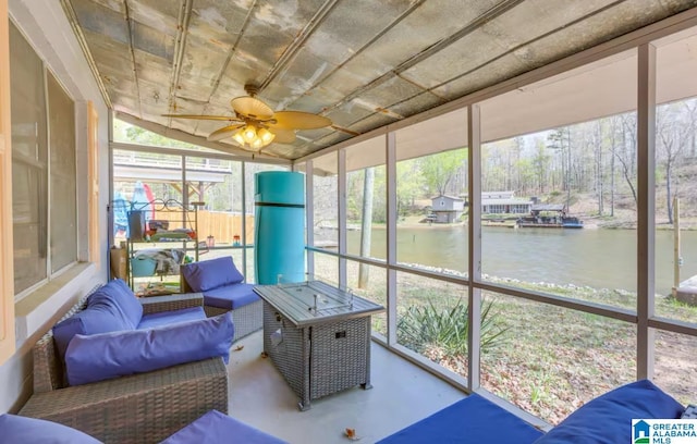 sunroom with ceiling fan and a water view