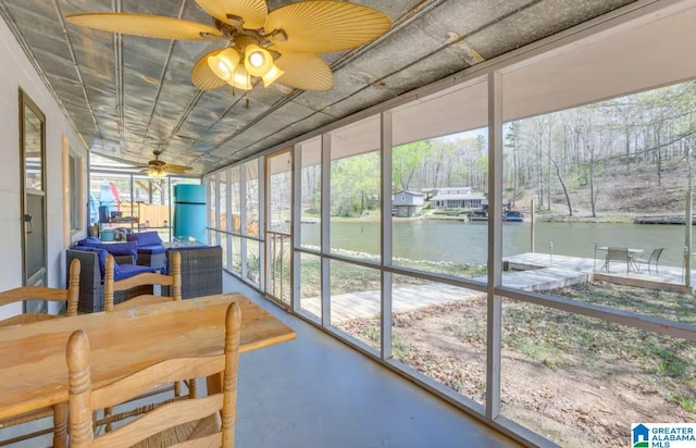 sunroom / solarium with ceiling fan and a water view