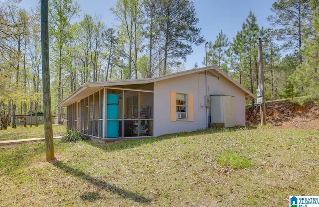 view of side of home featuring a sunroom, a yard, and cooling unit