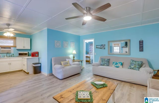 living room with ceiling fan, light hardwood / wood-style flooring, and sink