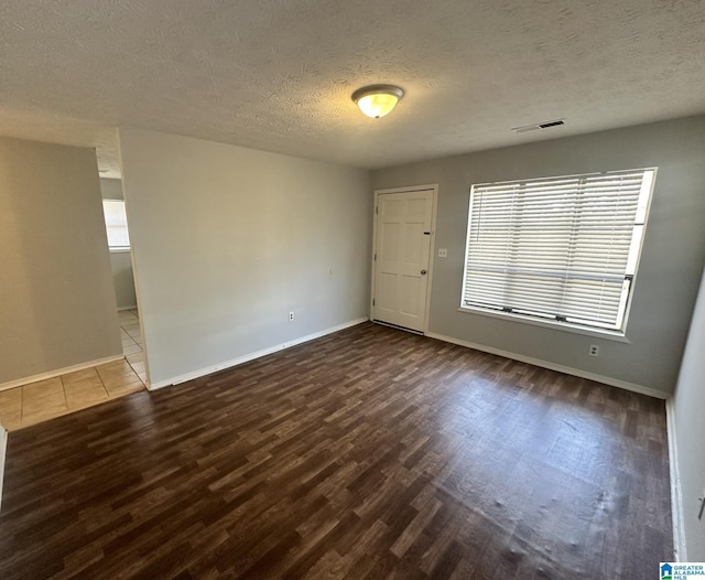 empty room with hardwood / wood-style floors and a textured ceiling