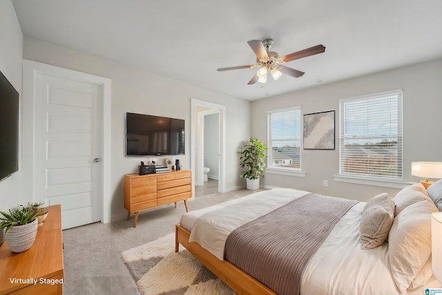 bedroom with light carpet, ensuite bath, and ceiling fan