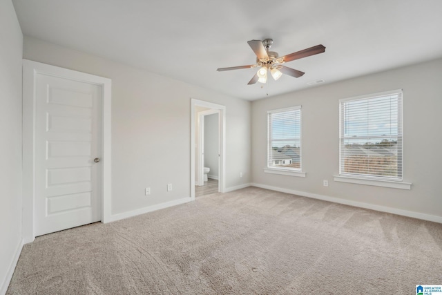 unfurnished bedroom with ceiling fan, light carpet, and ensuite bath