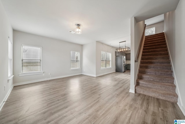 unfurnished living room featuring wood-type flooring and an inviting chandelier