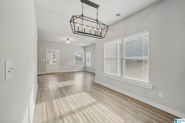 unfurnished living room with light hardwood / wood-style floors and a notable chandelier