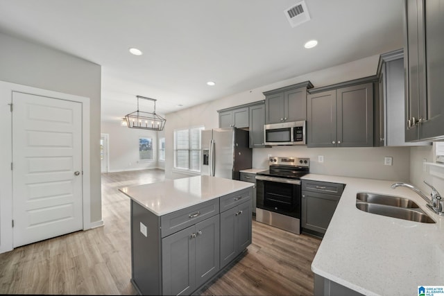 kitchen featuring a kitchen island, wood-type flooring, decorative light fixtures, and appliances with stainless steel finishes