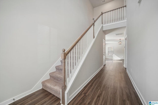 staircase featuring hardwood / wood-style floors and a towering ceiling