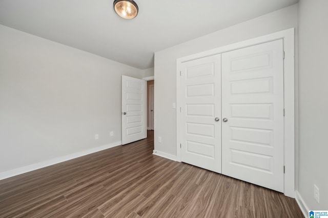 unfurnished bedroom with dark wood-type flooring and a closet