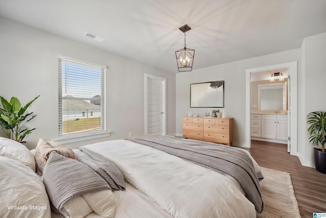 bedroom featuring ensuite bathroom, dark wood-type flooring, and a notable chandelier