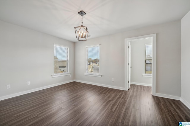 empty room featuring a chandelier and dark hardwood / wood-style flooring