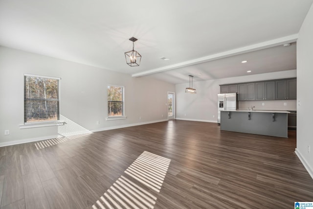 unfurnished living room featuring beam ceiling, sink, and dark wood-type flooring