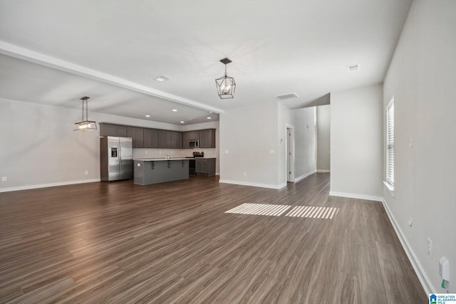 unfurnished living room featuring a chandelier and dark wood-type flooring