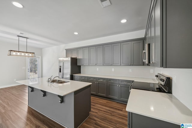 kitchen with stainless steel appliances, dark hardwood / wood-style floors, a center island with sink, and sink