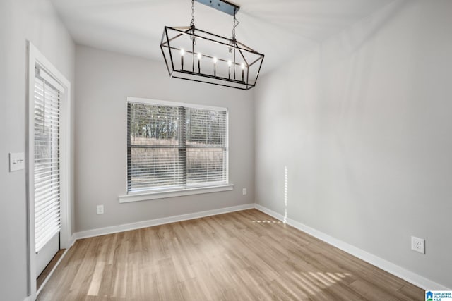 unfurnished dining area with a notable chandelier and light hardwood / wood-style floors