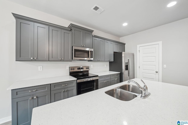 kitchen featuring light stone counters, stainless steel appliances, gray cabinets, and sink