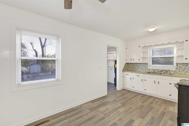 kitchen featuring hardwood / wood-style flooring, electric stove, tasteful backsplash, white cabinetry, and sink