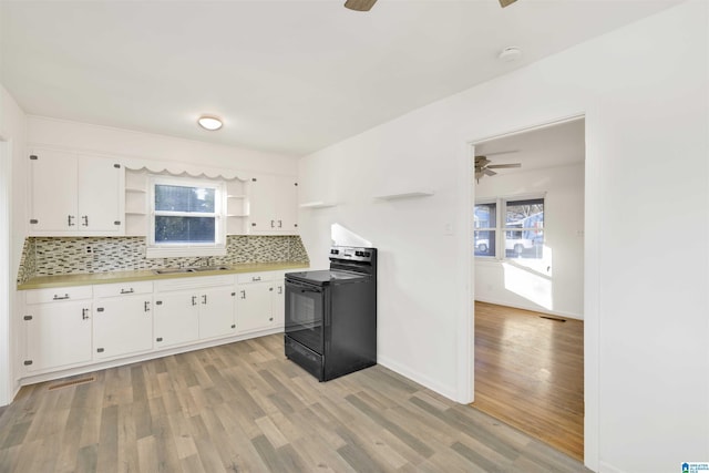 kitchen with sink, white cabinetry, black electric range oven, and light wood-type flooring