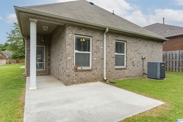 rear view of property featuring central air condition unit, a patio area, and a lawn