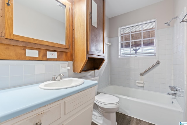 full bathroom featuring tiled shower / bath, tasteful backsplash, hardwood / wood-style flooring, toilet, and vanity