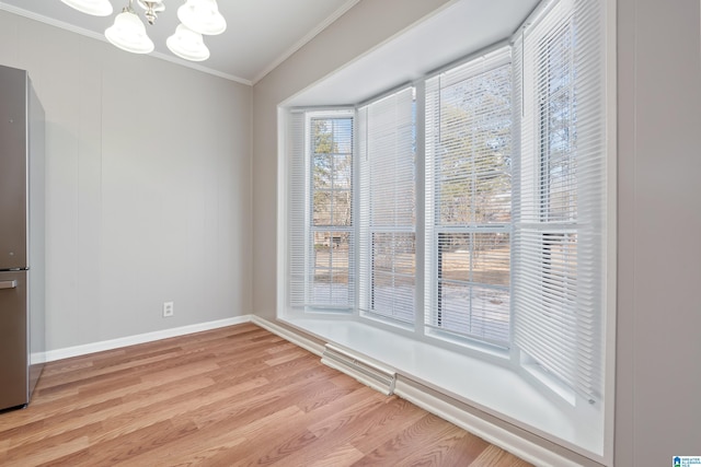 unfurnished dining area featuring crown molding, a notable chandelier, and light hardwood / wood-style flooring