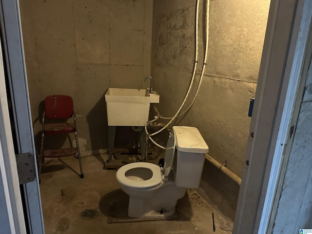 bathroom featuring toilet, concrete flooring, and sink