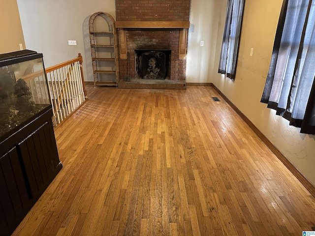 unfurnished living room featuring light hardwood / wood-style floors and a brick fireplace