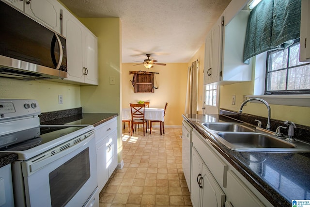 kitchen with sink, white appliances, white cabinetry, and a healthy amount of sunlight