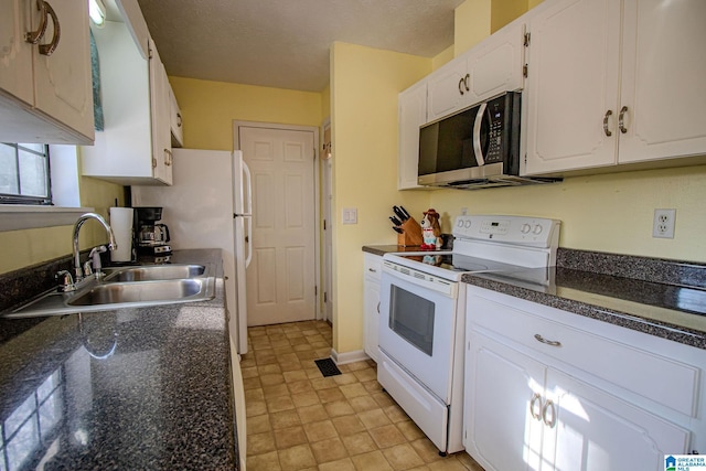 kitchen featuring white appliances, white cabinets, dark stone countertops, and sink