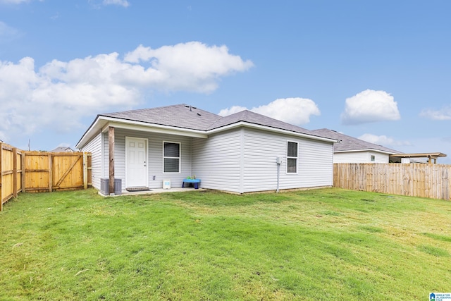 back of house with central air condition unit and a yard