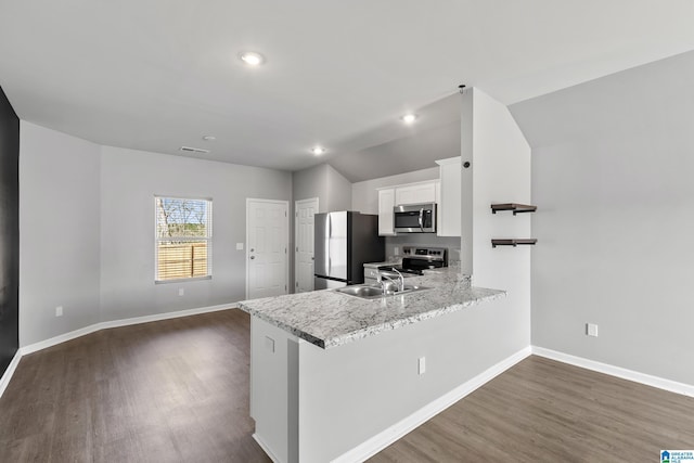 kitchen featuring vaulted ceiling, appliances with stainless steel finishes, kitchen peninsula, sink, and white cabinetry