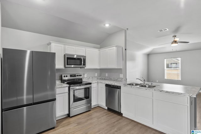 kitchen featuring vaulted ceiling, appliances with stainless steel finishes, kitchen peninsula, white cabinets, and sink