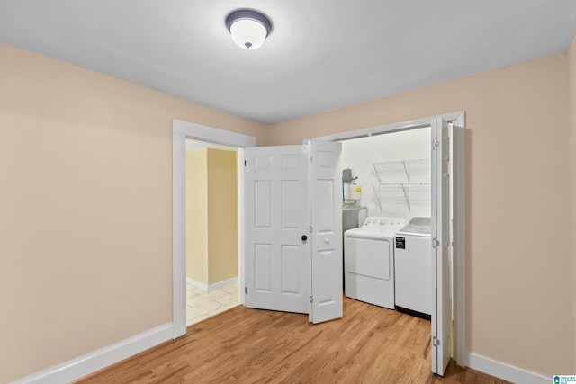 laundry area with separate washer and dryer and light hardwood / wood-style floors