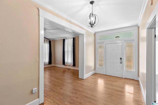 foyer entrance featuring light hardwood / wood-style flooring, an inviting chandelier, and crown molding