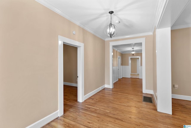 corridor featuring ornamental molding, light hardwood / wood-style flooring, and a chandelier