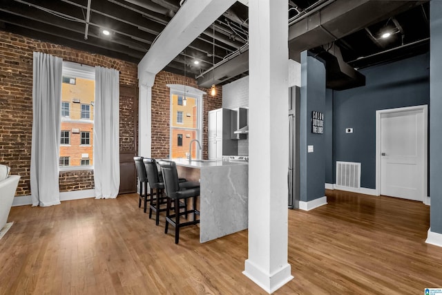 interior space featuring brick wall, light hardwood / wood-style floors, and sink