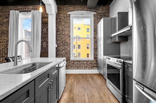 kitchen with brick wall, sink, and stainless steel appliances