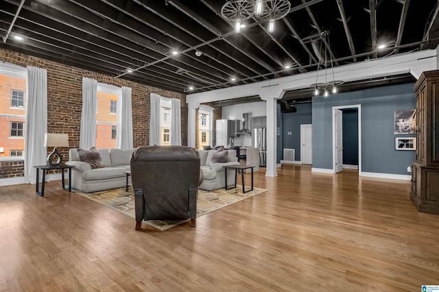 living room featuring wood-type flooring, brick wall, and a wealth of natural light