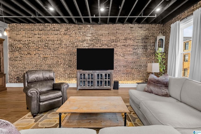 living room with hardwood / wood-style flooring and brick wall