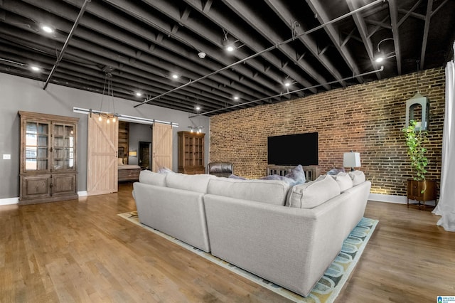 living room with brick wall, a barn door, and hardwood / wood-style flooring