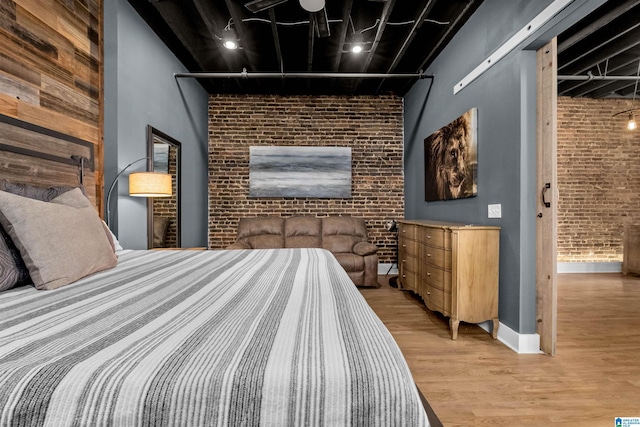 bedroom featuring light hardwood / wood-style floors and brick wall