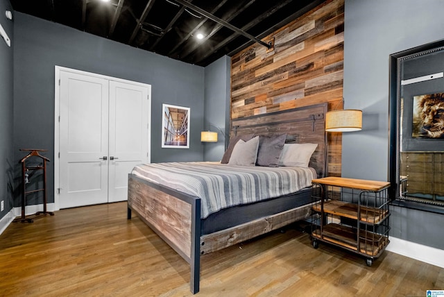 bedroom with a closet, wooden walls, and hardwood / wood-style floors