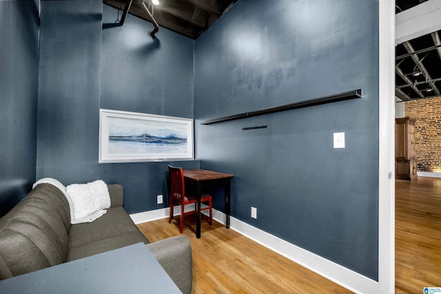 living area featuring brick wall and wood-type flooring