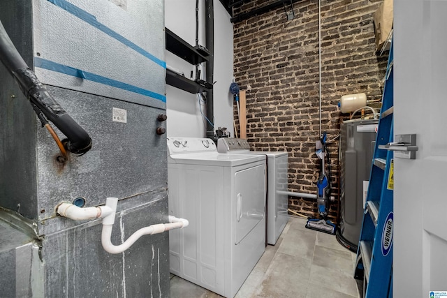 laundry area with water heater, separate washer and dryer, and brick wall