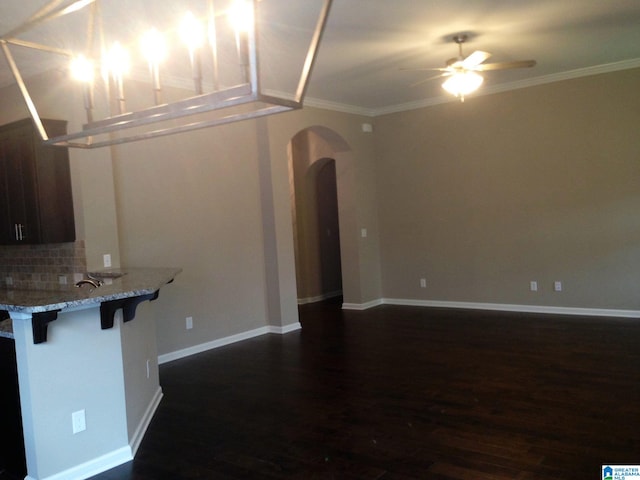 kitchen with ceiling fan, backsplash, crown molding, and a breakfast bar area