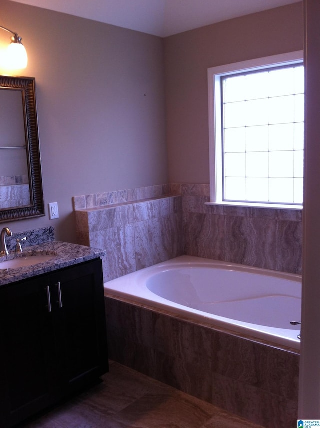 bathroom with tiled bath and vanity