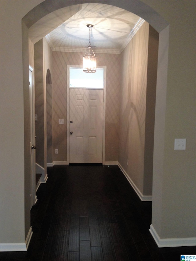 entryway featuring dark wood-type flooring, an inviting chandelier, and crown molding