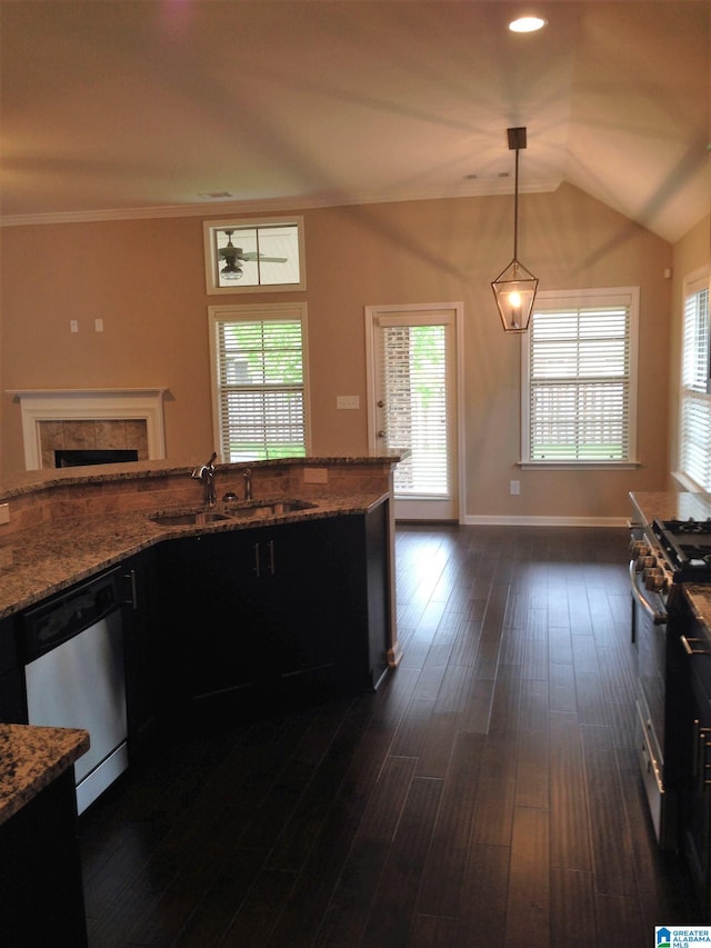 kitchen featuring sink, decorative light fixtures, a tile fireplace, light stone countertops, and appliances with stainless steel finishes