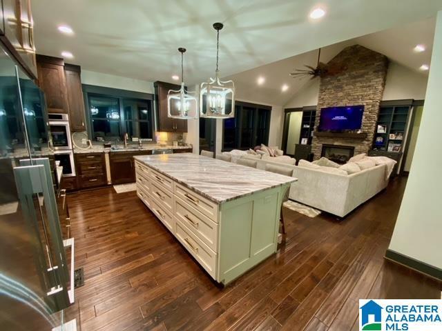 kitchen with light stone counters, a center island, a breakfast bar, lofted ceiling, and ceiling fan