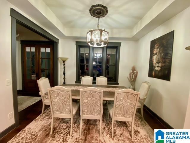 dining room with french doors, a raised ceiling, and a notable chandelier